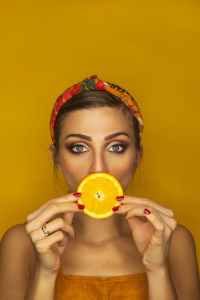 a woman covering her lips with an orange slice